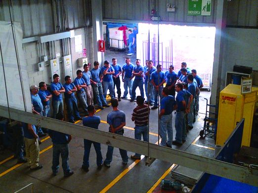 A group of Treasure Hunt team members in blue shirts gathered inside a plant near a loading area