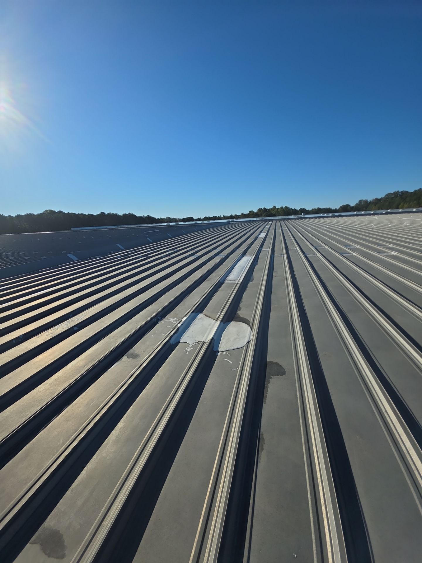 Before photo - Close-up view of the original roof surface, loose fasteners, and internal gutters prior to renovation